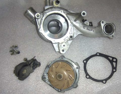 1997 Ford Taurus - A disassembled water pump assembly with its gasket, tensioner pulley, and mounting bolts laid out.