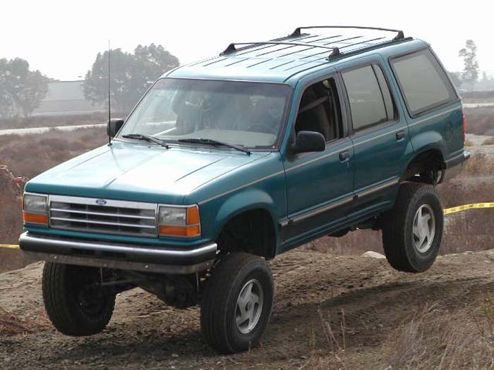 Teal Ford Explorer SUV with lifted suspension driving off-road