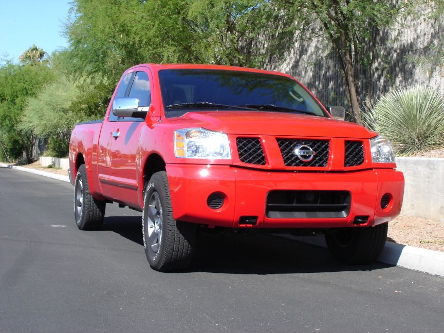 Red Nissan Titan king cab with painted red bumper, front 3/4 view