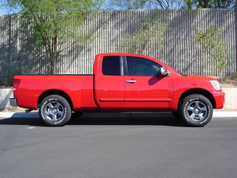 2005 Nissan Titan - Side profile of a red 2005 Nissan Titan pickup truck parked on asphalt.