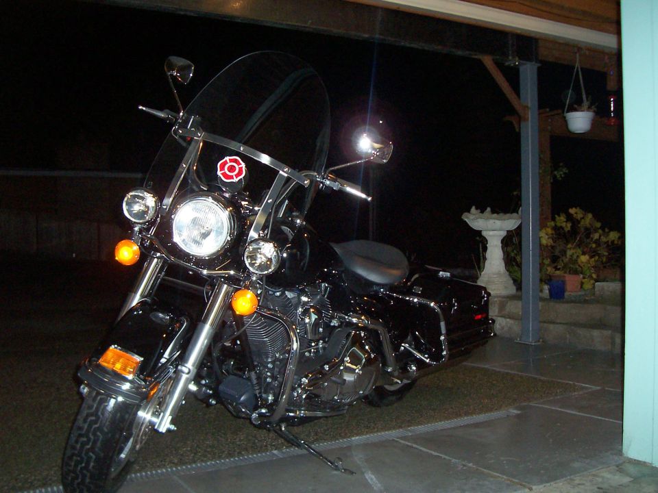 Black Harley-Davidson bagger with clear windshield and passing lamps parked at night