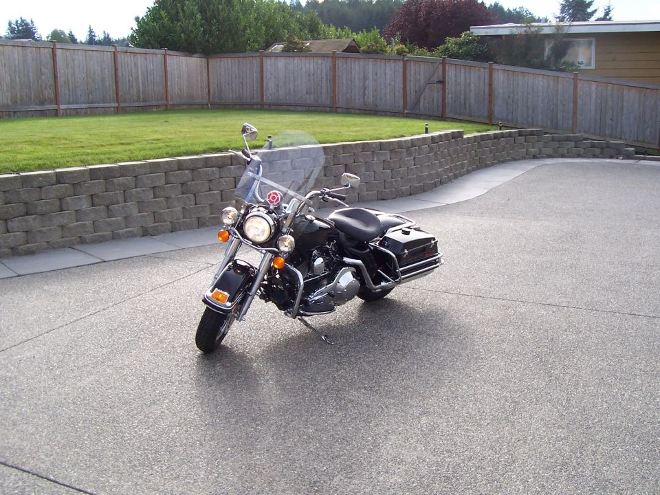 Black Harley-Davidson touring motorcycle parked on a concrete driveway by a lawn