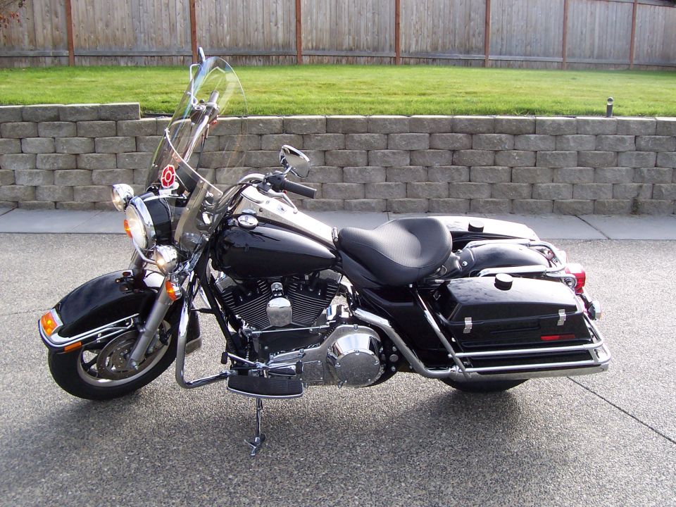 Black Harley-Davidson touring bagger with windshield and hard saddlebags on a driveway