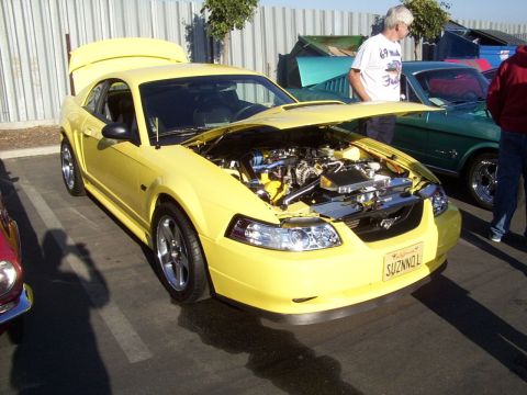 2002 Ford Mustang - A yellow Ford Mustang is displayed with its hood and trunk open, revealing the engine and interior.