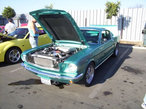 2002 Ford Mustang - A classic green Mustang from the mid-1960s is displayed with its hood open, revealing the engine compartment.