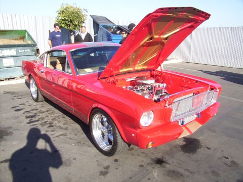 2002 Ford Mustang - Classic red Ford Mustang parked outdoors with its hood open, revealing the engine bay.