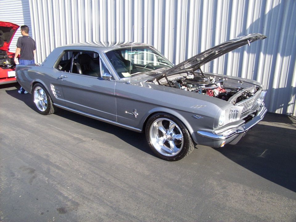 Gray 1965 Ford Mustang coupe with hood open, parked next to a red car