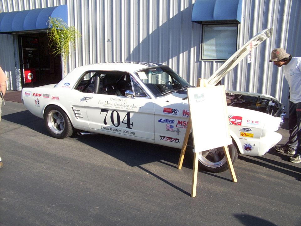 White 1965 Ford Mustang coupe with racing decals and number 704