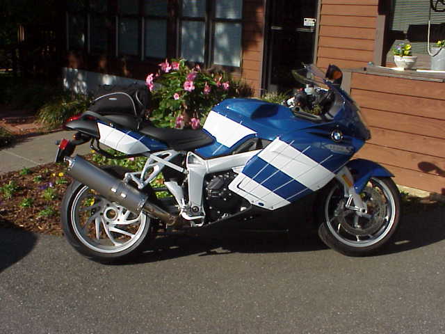 Blue and white BMW sport motorcycle parked in left-side view near flowers