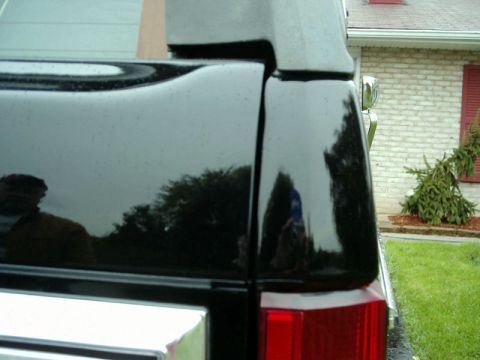 1984 Ford Bronco - Close-up of a black SUV's rear corner, showing reflections of the surroundings.