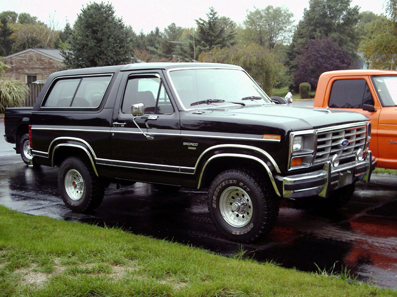 Black Ford Bronco with chrome grille and polished wheels parked on a wet driveway