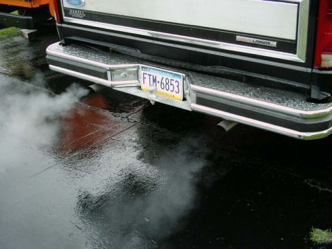 1984 Ford Bronco - Smoke billows from the exhaust of a Ford truck on a wet, reflective surface.