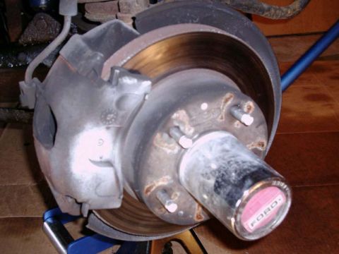 1988 Ford Bronco - A close-up view of a vehicle's brake system, including a rotor, caliper, and a Ford hubcap.