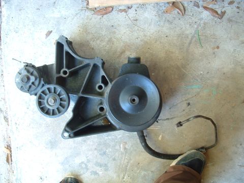 1993 Ford Bronco - A detached power steering pump assembly rests on a concrete surface.