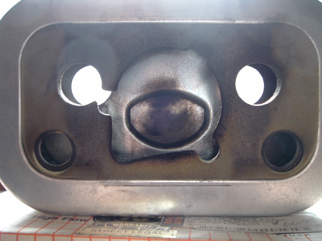 Close-up of a motorcycle engine part with two circular openings and a central oval shape