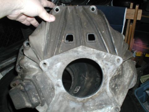 1979 Ford Bronco - A dirty engine block is held by a hand, with a large opening in the center and two square holes above.