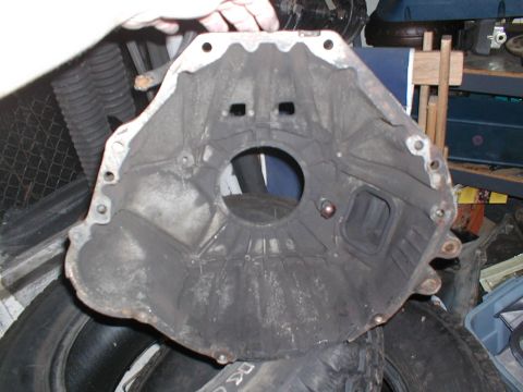1979 Ford Bronco - A transmission bell housing is shown from the front, resting on tires.