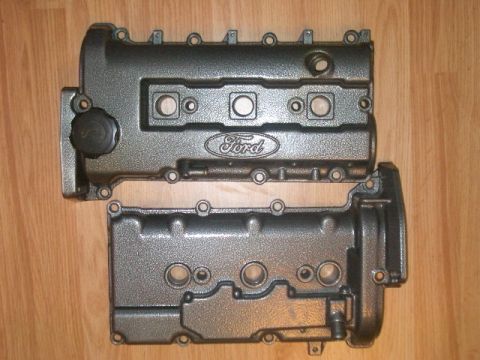 1997 Ford Probe - Two Ford engine valve covers are shown, one with an oil cap and Ford logo, resting on a wooden surface.