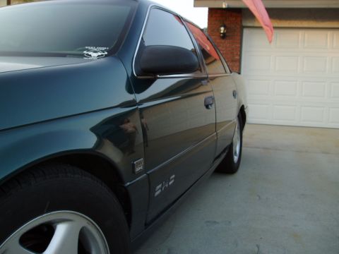 1993 Ford Taurus - Side view of a 1993 Ford Taurus sedan, showing its body lines and a sticker on the windshield.