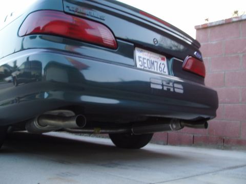 1993 Ford Taurus - The rear of a dark green 1993 Ford Taurus SHO is shown with its license plate and dual exhaust pipes visible.