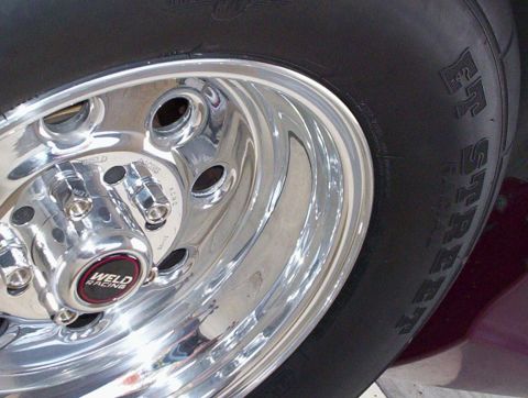 1992 Ford Crown Victoria - Close-up of a polished Weld Racing five-lug drag wheel with a red-and-black center cap and open lug holes, wrapped in a wide Mickey Thompso…