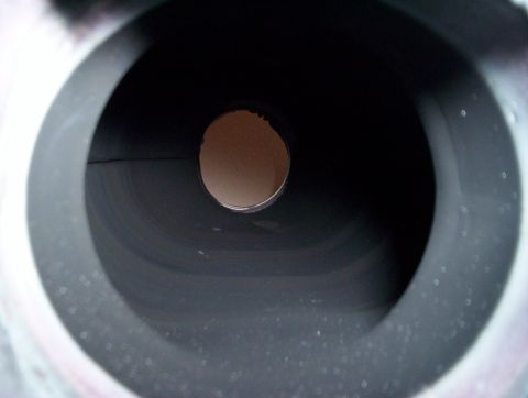 1992 Ford Crown Victoria - A view into the dark opening of an engine intake manifold, showing a central circular hole.