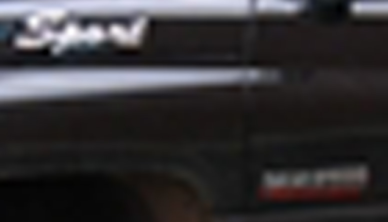 Close-up of a chrome emblem on a dark vehicle, possibly a Ford F-Series truck