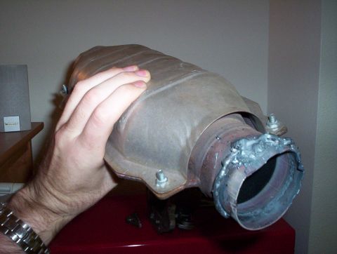 1992 Ford Crown Victoria - A catalytic converter is shown being held, with a close-up view of its welded inlet pipe.