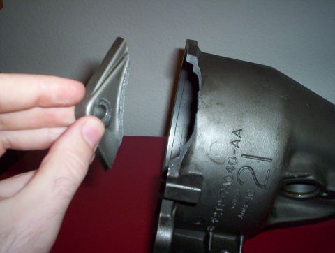 1992 Ford Crown Victoria - A hand holds a broken piece of metal next to a housing that has the part number F2TP-74040-AA stamped on it.
