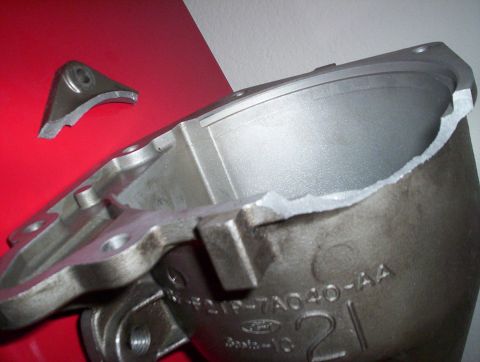 1992 Ford Crown Victoria - A damaged transmission case shows a large crack and a separate broken piece, with part numbers visible on the metal.