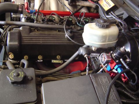 1992 Ford Crown Victoria - Close-up view of an engine bay, highlighting the fuel pressure regulator and brake fluid reservoir.