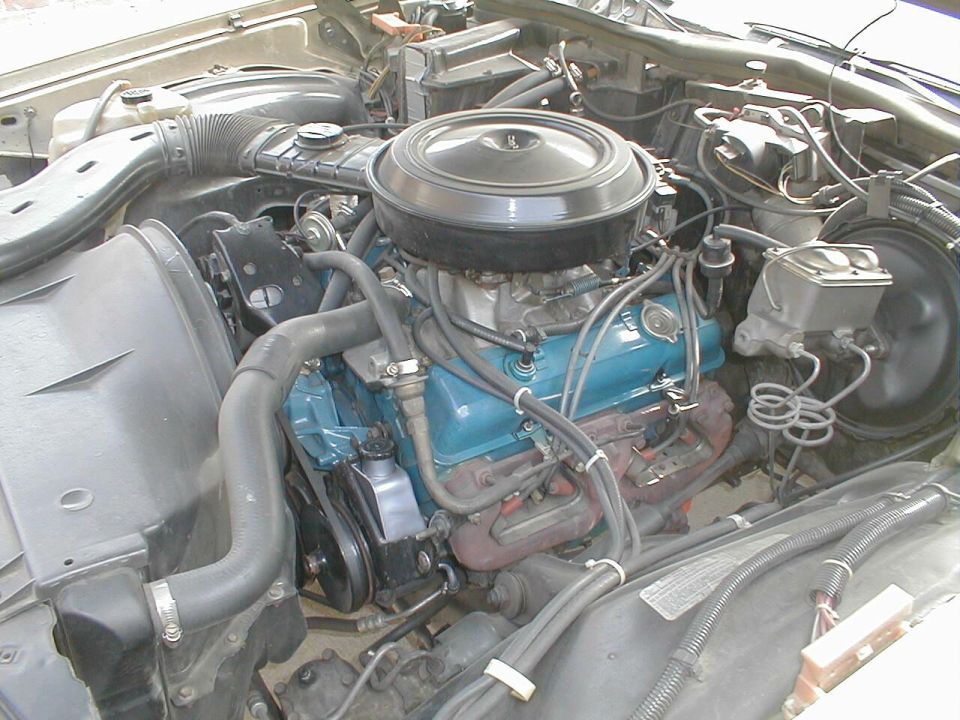 V8 engine bay with teal valve covers and round black air cleaner