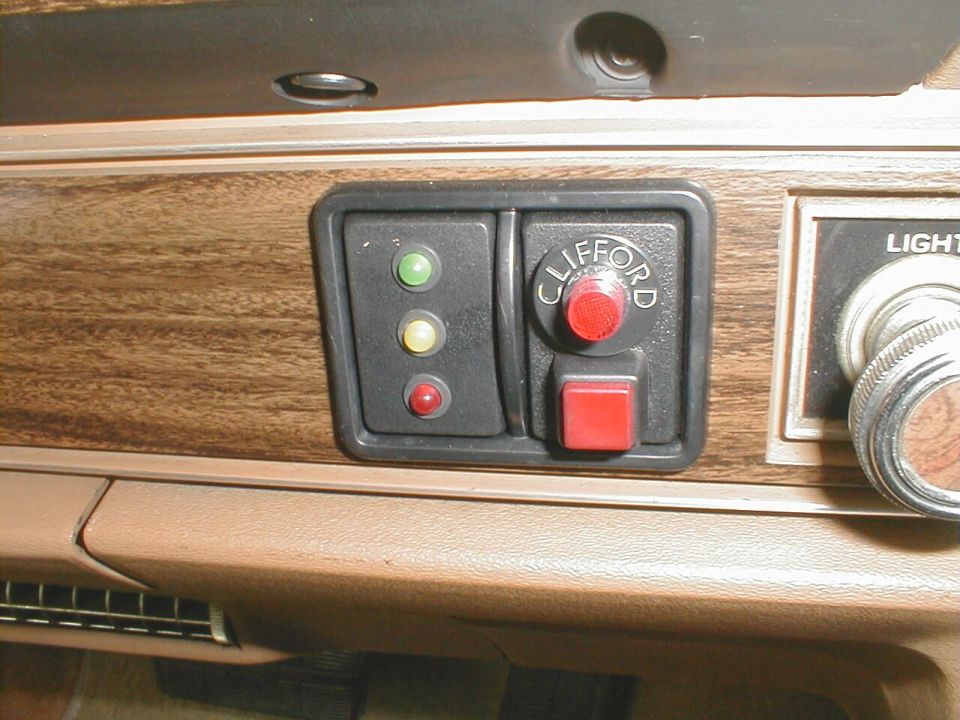 Clifford alarm indicator lights and valet button mounted in a woodgrain car dash