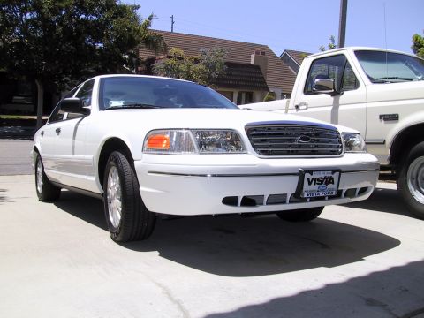2003 Ford Crown Victoria - Front view of a white 2003 Ford Crown Victoria, parked next to a pickup truck.
