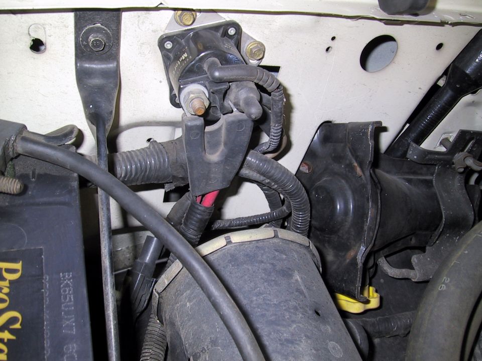 Engine ignition coil and wiring with visible text on battery
