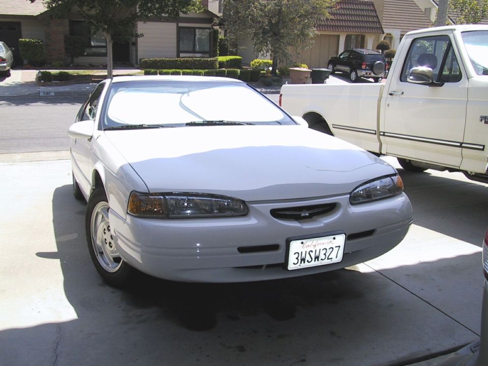 1997 Ford Thunderbird parked in driveway next to a white pickup truck
