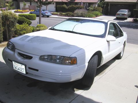 1997 Ford Thunderbird - A white coupe is parked in a suburban driveway, with another car visible in the background.