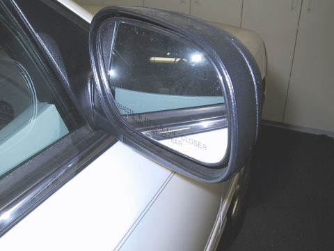 2003 Ford Crown Victoria - The side mirror reflects the interior of a garage, showing the text 'Objects in mirror are closer than they appear'.