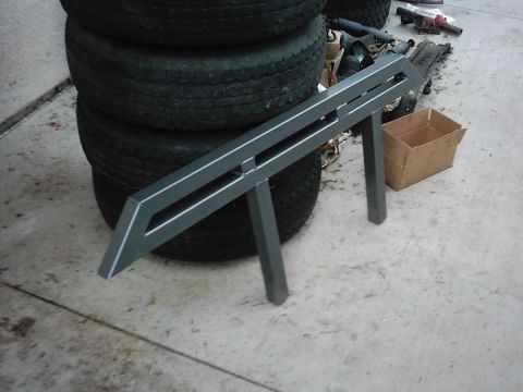 1978 Ford Bronco - A custom metal fabrication part is shown in front of a stack of tires, with a cardboard box in the background.