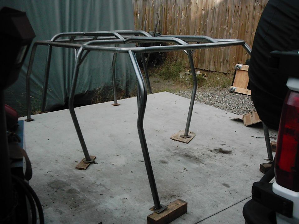 Custom metal roll cage frame on concrete pad with wooden blocks