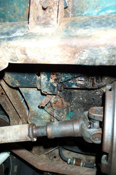 1954 Jeep Wrangler - Close-up of the undercarriage, revealing significant rust and mechanical components like the driveshaft and fuel filter.