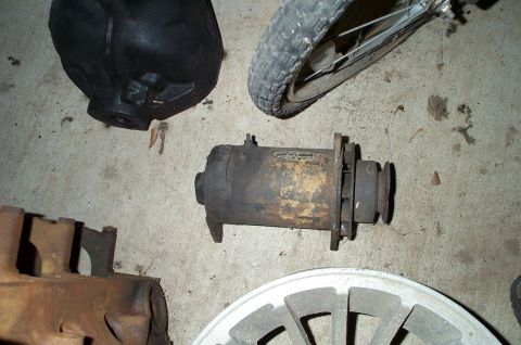 1954 Jeep Wrangler - Various automotive parts, including a generator and a tire, are laid out on a concrete surface.