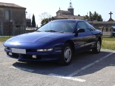 1994 Ford Probe - Blue coupe parked in a lot with a church and cemetery in the background.