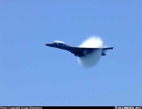 1987 Ford Bronco - A jet aircraft is captured in flight, generating a visible condensation cloud as it exceeds the speed of sound.