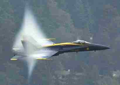 1987 Ford Bronco - A Blue Angels jet fighter aircraft is captured in flight, generating a visible vapor cone.