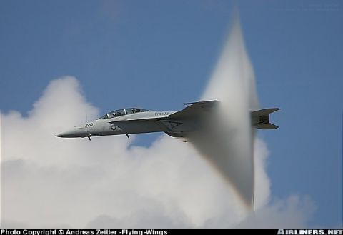 1987 Ford Bronco - A fighter jet is captured in flight, generating a visible vapor cone as it exceeds the speed of sound.