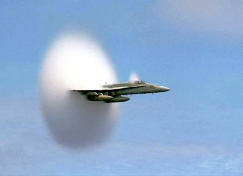 1987 Ford Bronco - A jet aircraft is shown creating a visible shock cone as it breaks the sound barrier in the sky.
