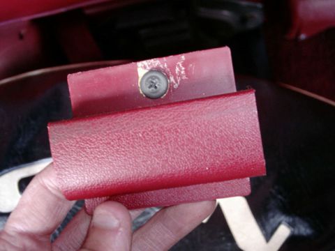 1984 Ford Bronco - Close-up of a red interior trim piece, possibly a handle or cover, with a visible screw.