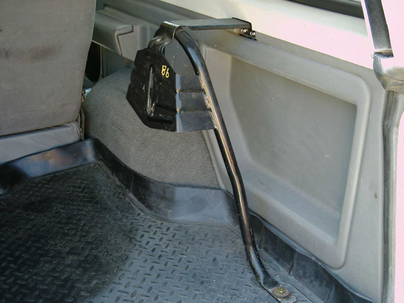 Vehicle interior corner with black rubber mat, gray carpet, and black tube routed to floor