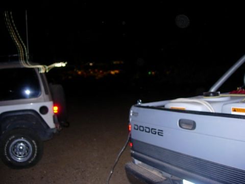 1981 Ford F-150 - A Dodge pickup truck bed carrying a water tank is parked next to a Jeep Wrangler in this nighttime scene.